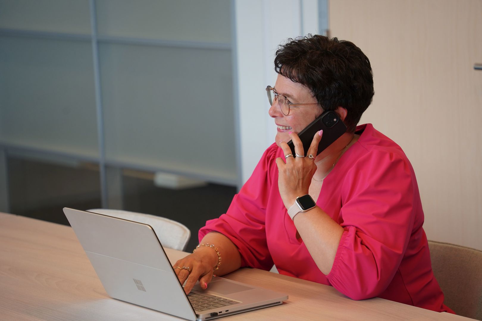 Dame aan het werk bij Zaffier achter een laptop en aan de telefoon.
