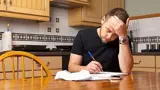 Man Nadenkend Aan Keukentafel Met Papier En Pen