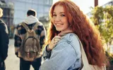 Meisje met rood haar, sproeten en rugtas over de schouder